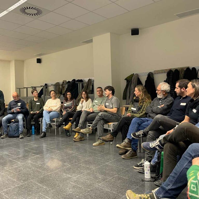 Group of people sitting in a circle in a room, participating in a collective reflection session in an informal and collaborative environment.